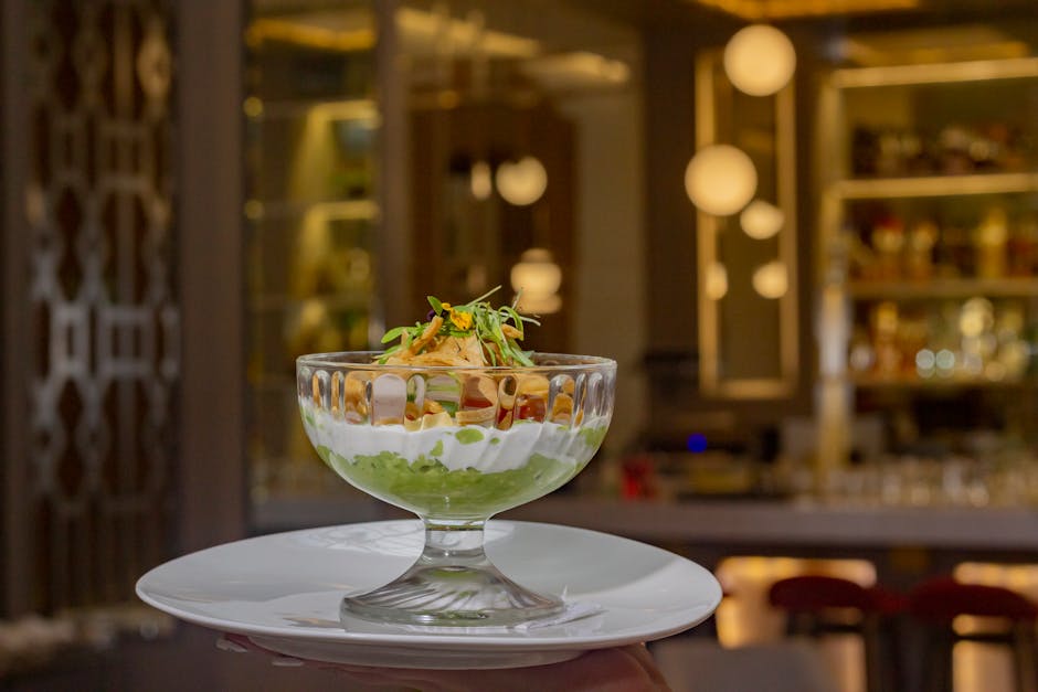 A close-up of an elegant dessert glass bowl in a stylish, ambient restaurant setting.